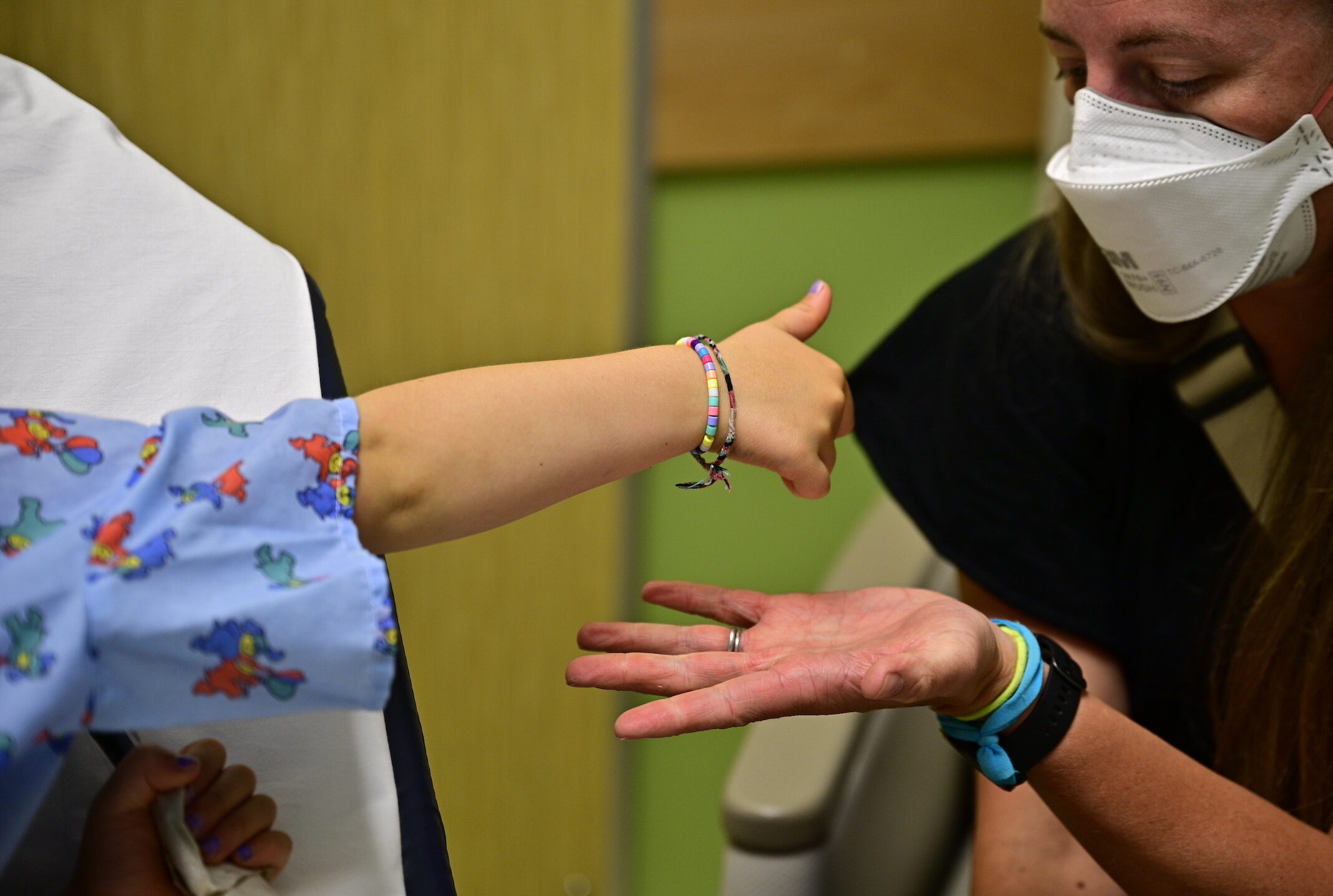 A child wearing a hospital gown reaching for a woman's outstretched hand