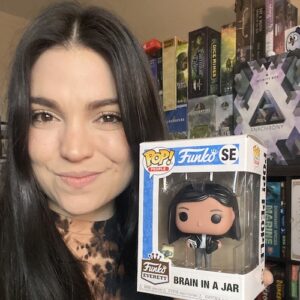 woman with brown hair smiling and holding box with bobblehead toy