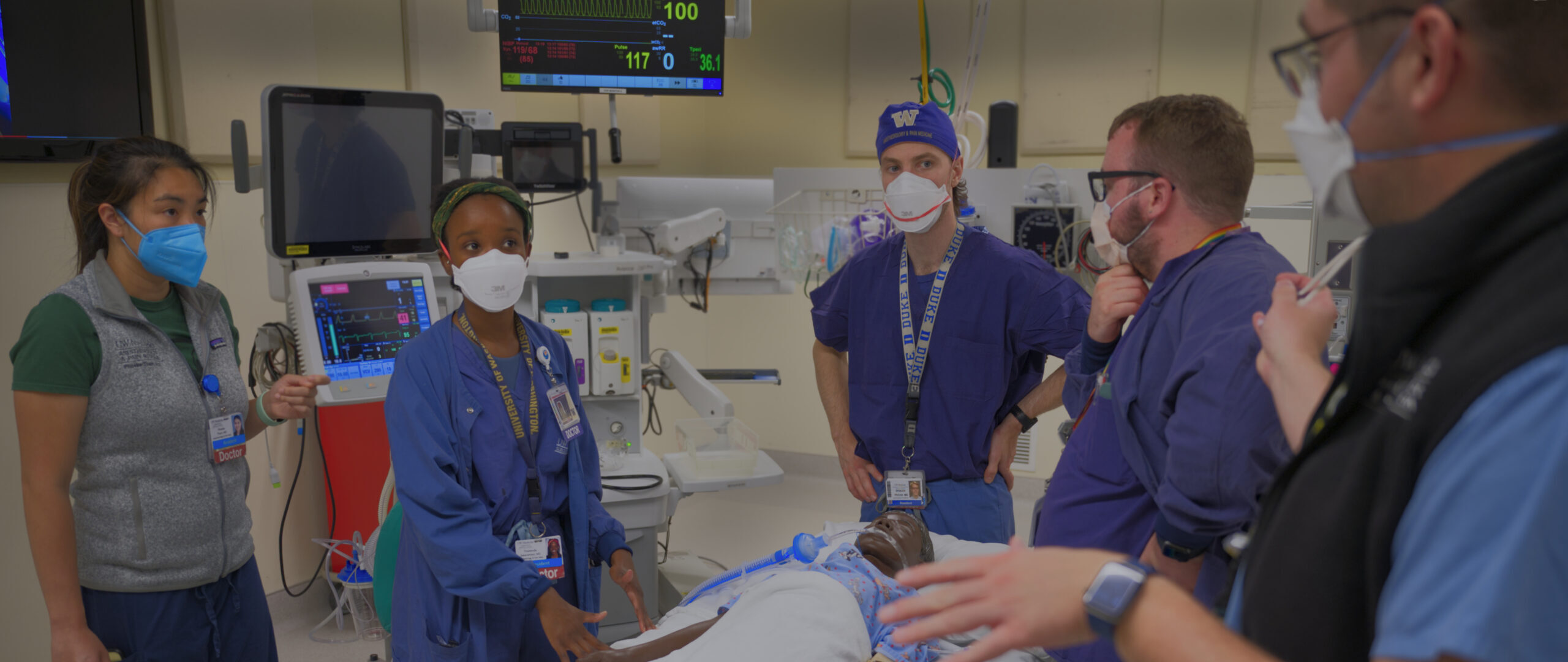 Five trainees standing over a simulation lab manikin.