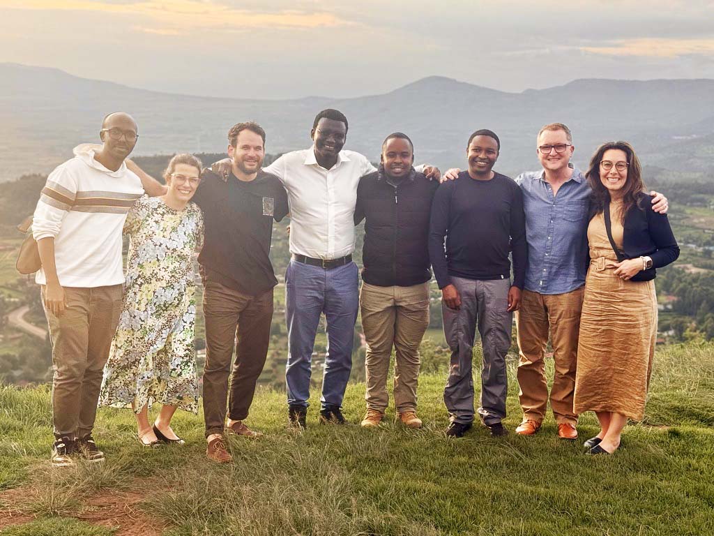 Drs. Tischler and Daher posing for a photo with UW-GAIN and University of Nairobi faculty. They are standing outside on the grass with Kenyan mountains behind them.