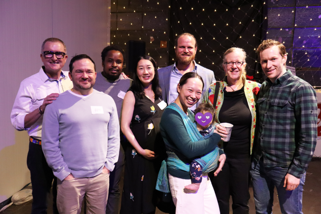 Eight members of the UW-GAIN event planning committee, smiling, looking into the camera. See caption for details.
