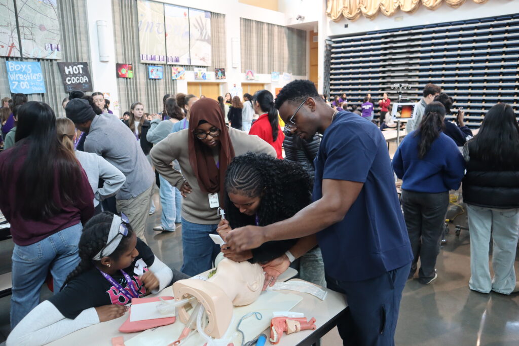 Several students observe an anesthesiology resident who is demonstrating airway intubation on a manikin.