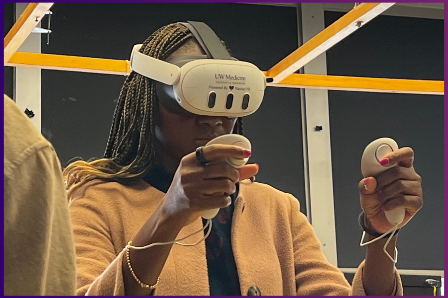 Dr. Bukola Ojo, co-director of residency simulation, is wearing a virtual reality headset and holding controls in her hands. She has long braided hair and is wearing a yellow sweater.