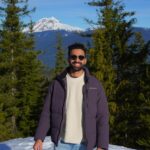Dr. Zaidi in the mountains, a snow white peak behind him.