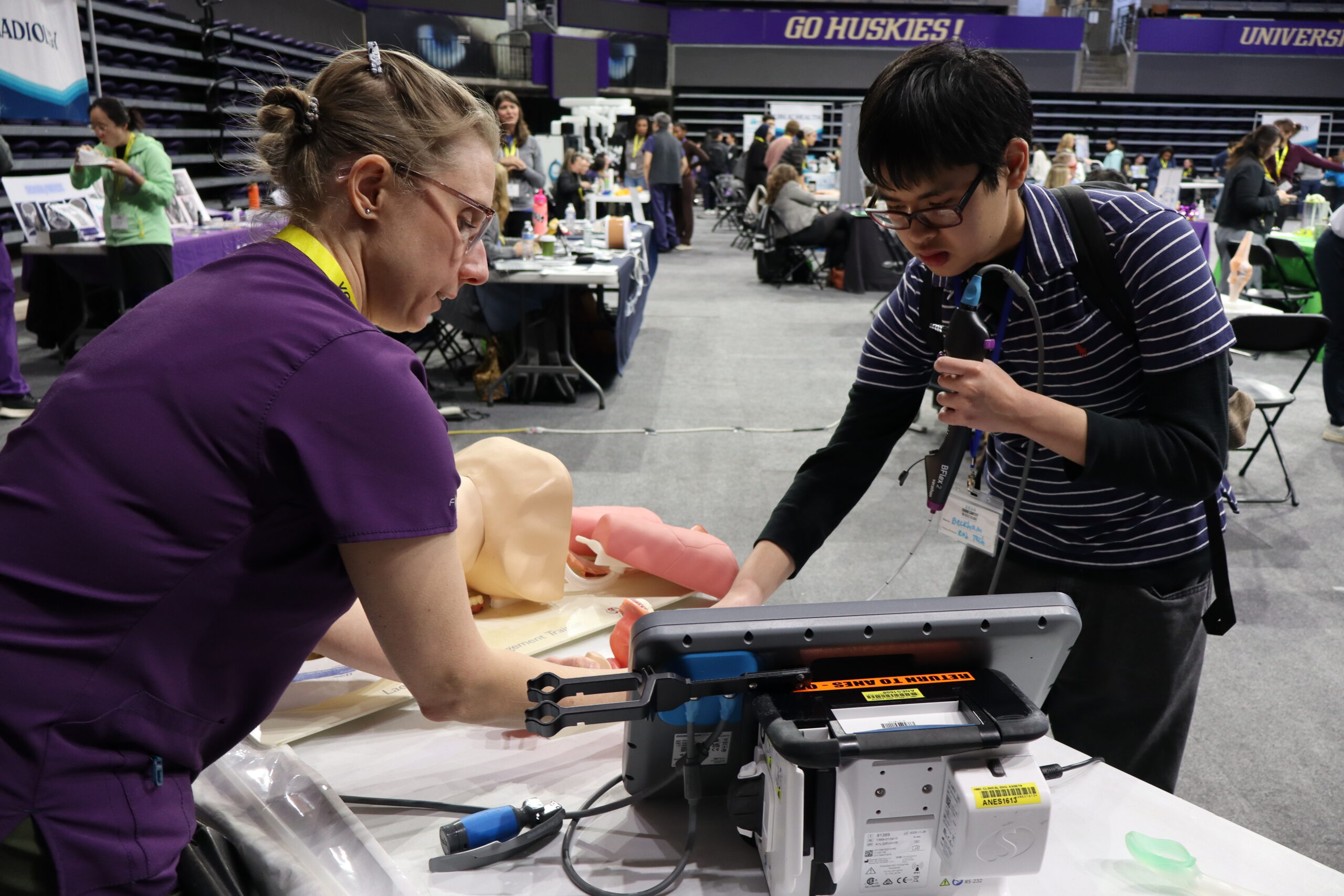 A woman demonstrates airway intubation to a high school student.