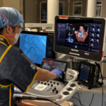 Dr. Richard Sheu, in scrubs, looks at imaging on OR monitor.