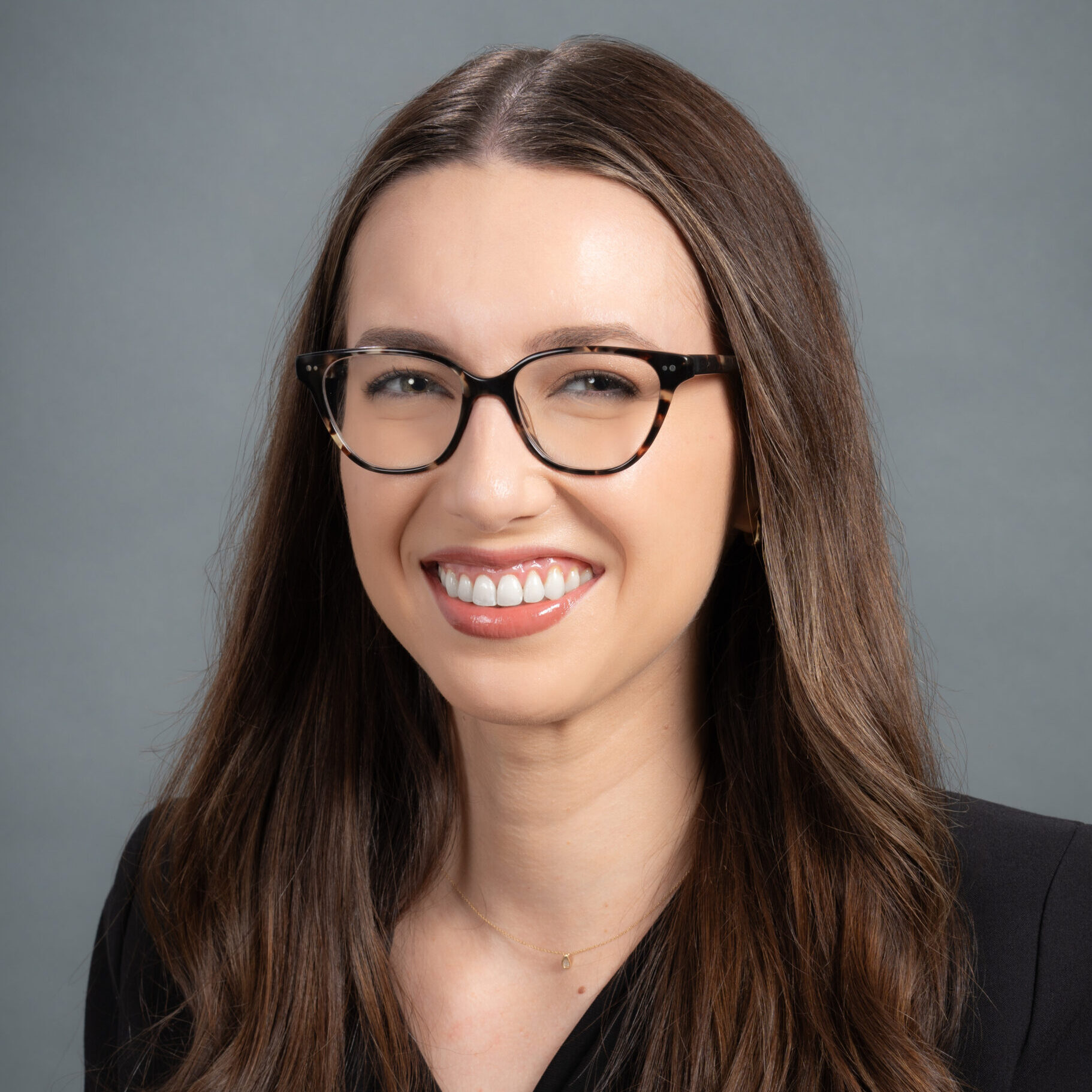 Karina has long dark hair and wears glasses.
